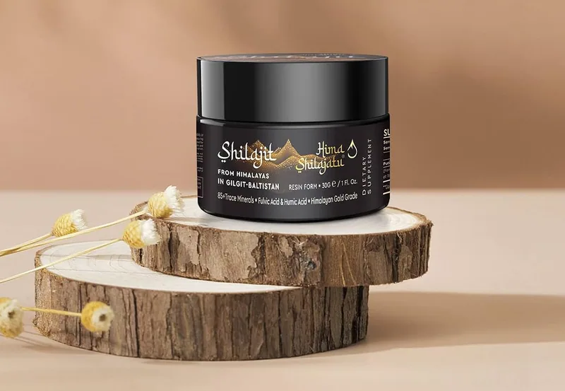 The jar of Hima Shilajatu shilajit resin on wood slices, with dried flowers beside it